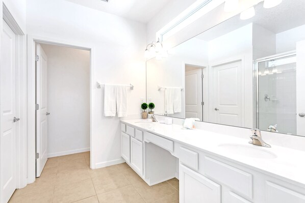 A modern bathroom with white fixtures, a large mirror, and a beige tiled floor. - Upstay: Sonoma Resort Mansion w/ Pool & Games Room (Kissimmee)