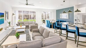 Un salon moderne avec un canapé, une table basse et un coin repas doté de chaises bleues.