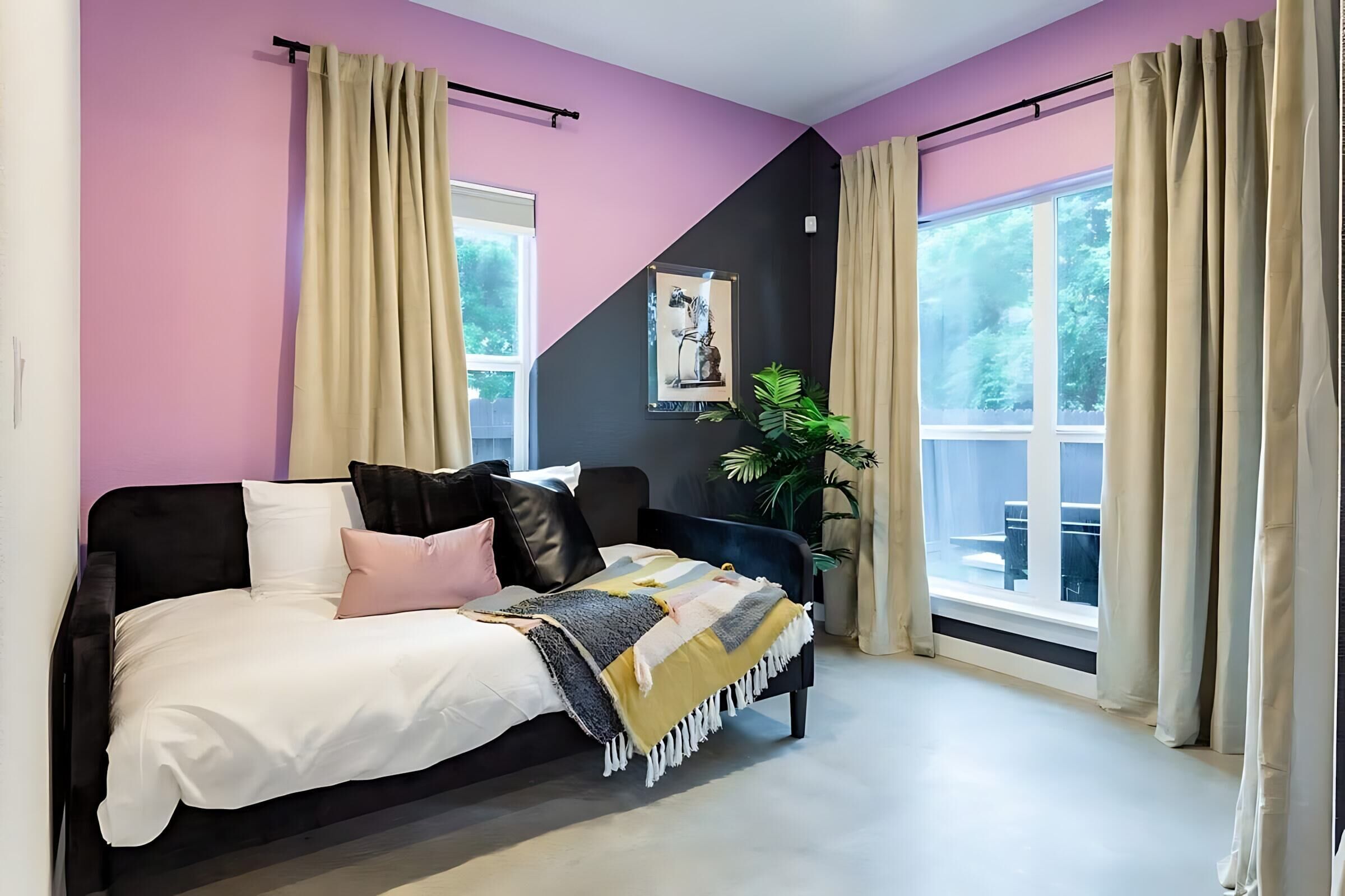A bedroom with a bed, a plant, and a window.