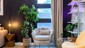 A modern living room with a white armchair, a round table, and a floor lamp. - East Austin Pool and Hot Tub Retreat Near Rainey (Austin)
