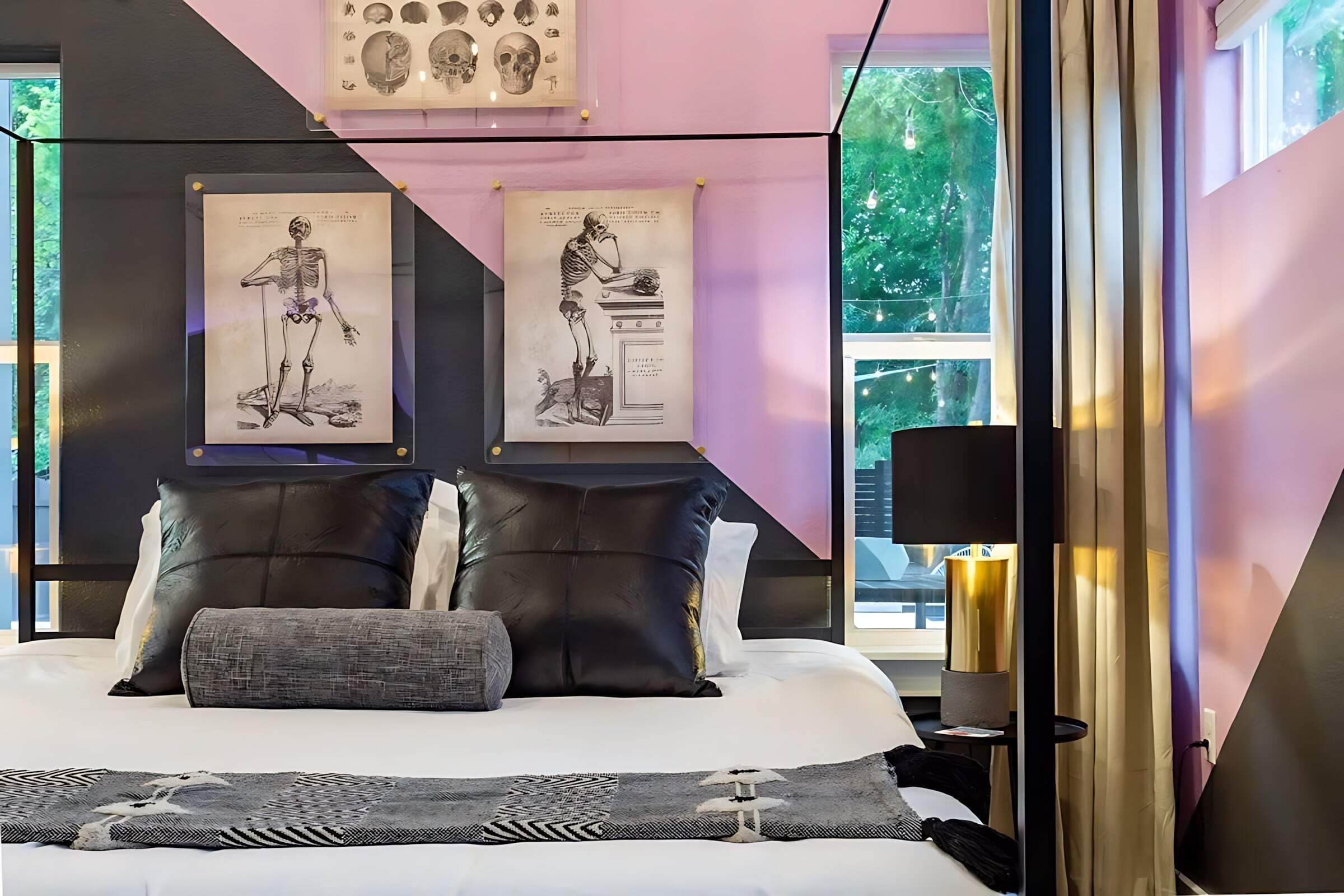 A modern bedroom with a bed, pillows, a nightstand, a lamp, and framed anatomical illustrations on the wall.