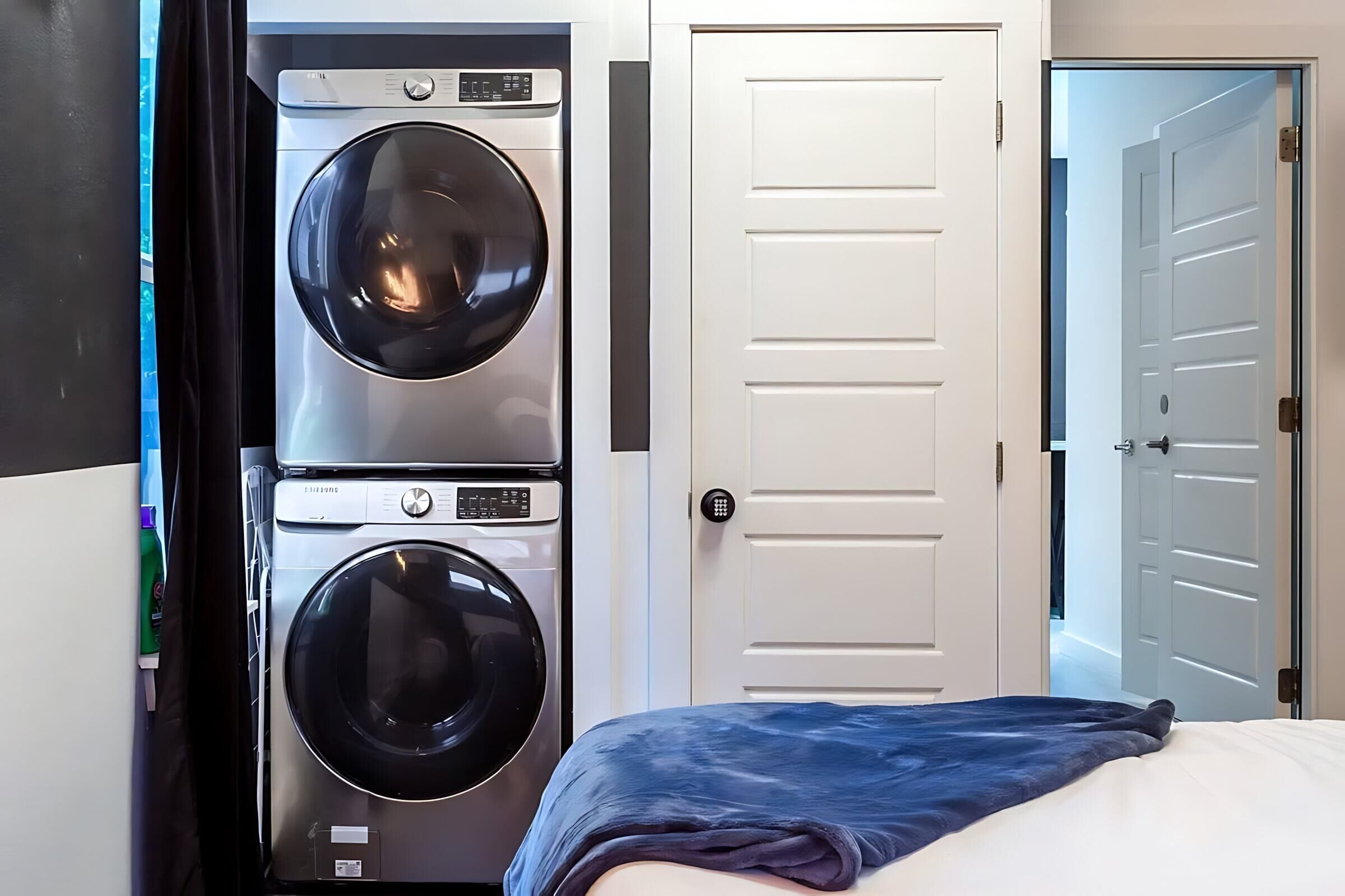 A laundry room with two stacked washing machines and a white door.