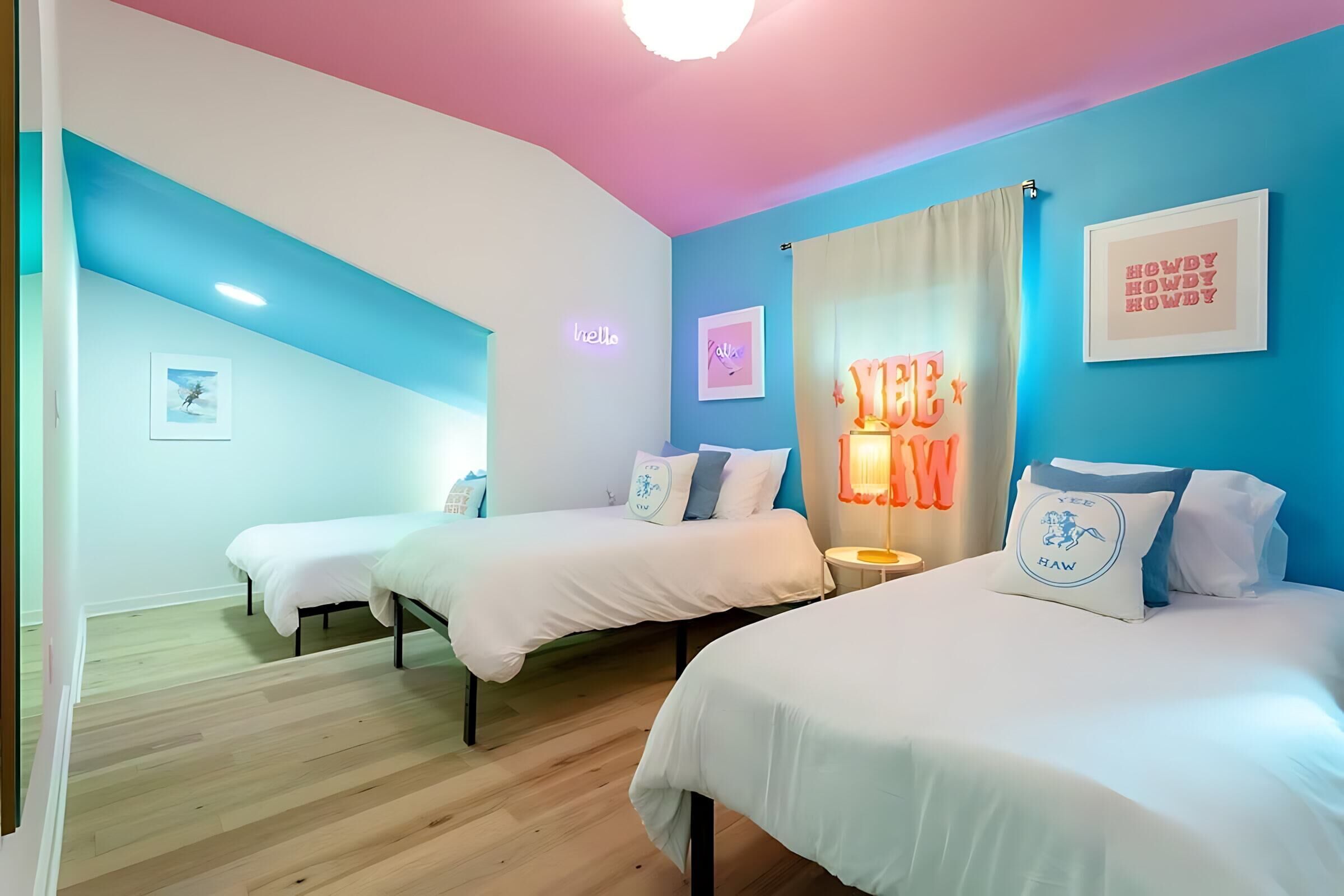 Een kamer met drie bedden, een neonbord en een blauwe muur.