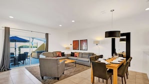Un salon moderne avec un canapé, une table basse et un coin repas comprenant des chaises et une table mise pour un repas.