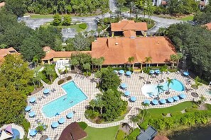 An aerial view of a resort with a large pool area, multiple lounge chairs, and a well-maintained garden. - Upstay Spacious 3BR Home w/ Resort Clubhouse Pool (Kissimmee)