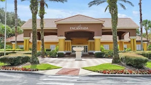 L’entrée d’un hôtel, agrémentée d’une enseigne portant le nom « Encantada », est entourée de palmiers et d’un aménagement paysager soigné.