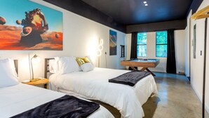 Habitación de hotel con dos camas, una mesa de billar y un cuadro grande de una mujer en un planeta.