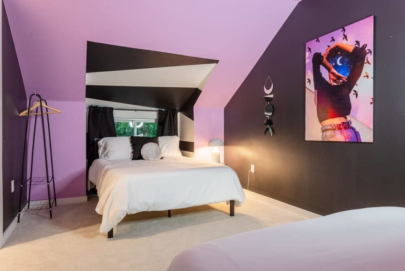 A bedroom with a bed, a hanging light fixture, and a painting on the wall.