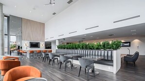 A modern hotel lobby with a central seating area, a bar, and a TV screen. - Stylish 1BR Condo w Balcony & Skyline Views (Kitchener)