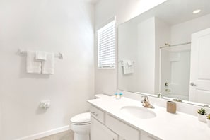 A modern bathroom with a white sink, a large mirror, and a toilet. - Garden View 6BR Escape With Pool, Hot Tub & Games (Kissimmee)