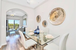 Uma área de jantar moderna com mesa de vidro, cadeiras brancas e pratos decorativos.