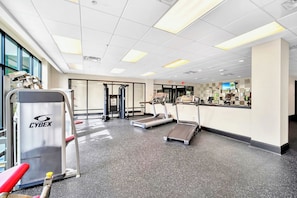 Een fitnessruimte met loopbanden, een Cybex-apparaat en een halterbank.