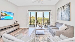 Ein Wohnzimmer mit Fernseher, einer Couch, einem Couchtisch und einem Balkon mit Blick.