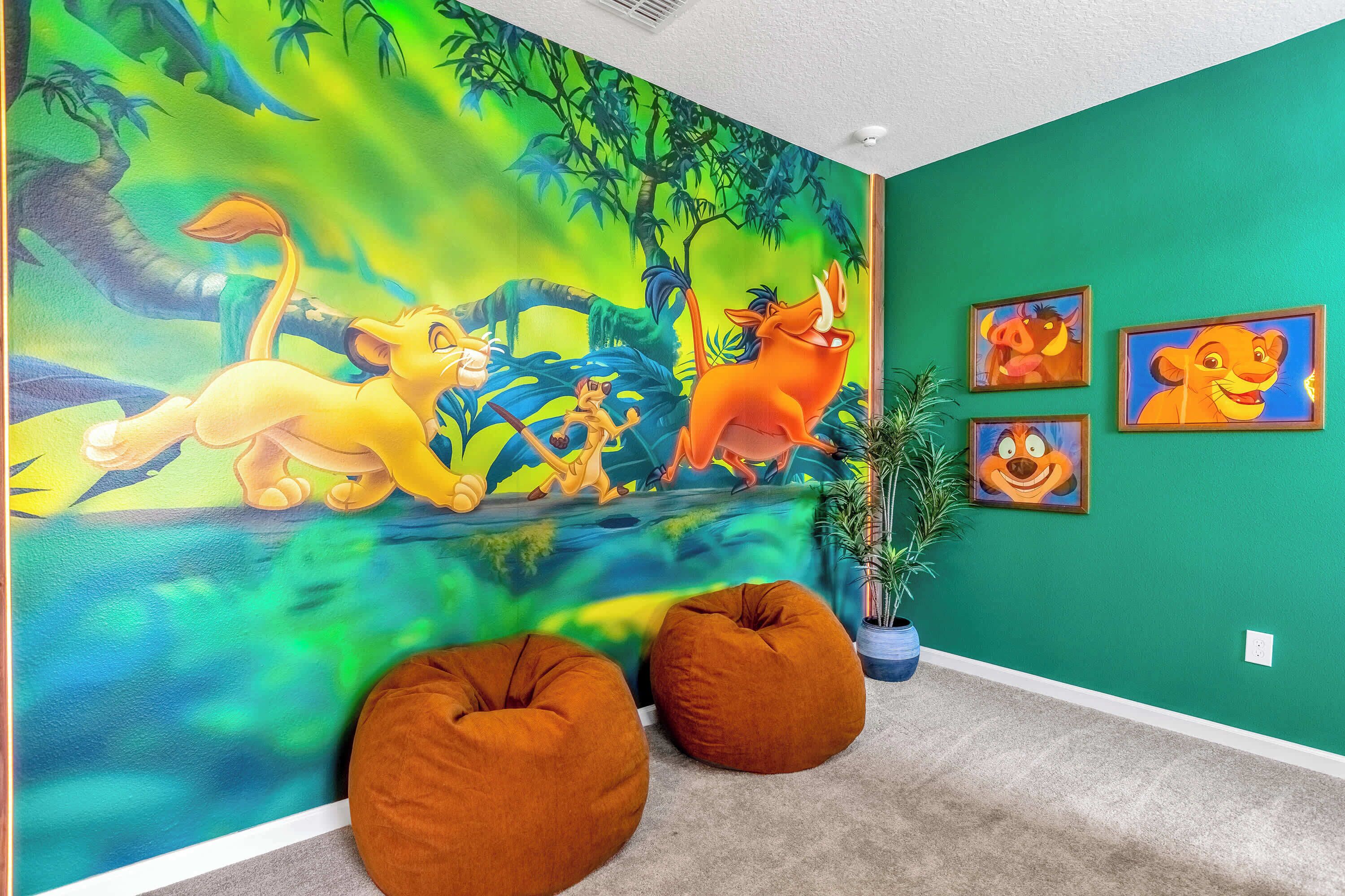 A room with a vibrant mural of animated characters, two bean bag chairs, and framed pictures on the wall.