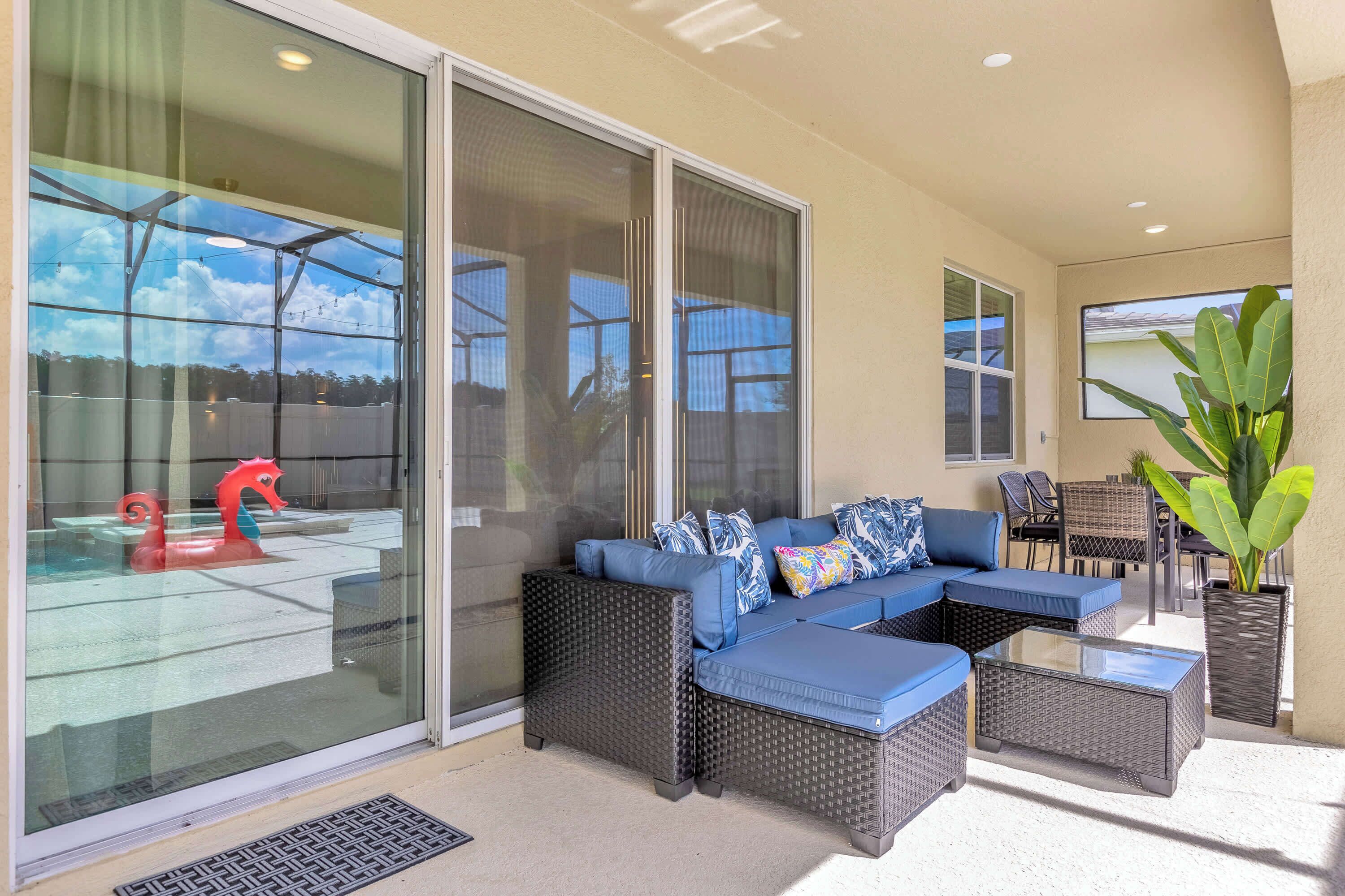 An outdoor patio area with a sectional sofa, a glass table, and a potted plant.