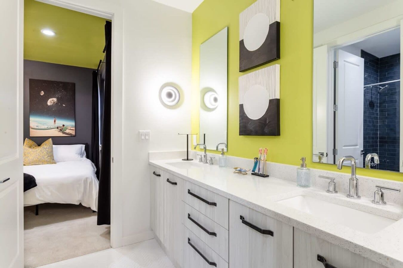 Un baño moderno con muebles blancos, lavamanos doble y un espejo grande.