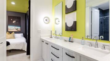 Un baño moderno con muebles blancos, lavamanos doble y un espejo grande.