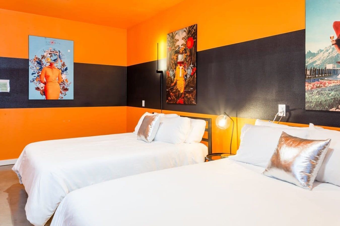 Ein Hotelzimmer mit zwei Betten, orangefarbenen und schwarzen Wänden sowie Bildern an den Wänden.
