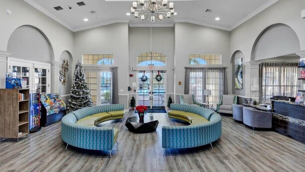 A spacious lobby with a central seating area, large windows, and a modern chandelier. - Upstay Great 3BR Condo w Scenic Views & Patio (Orlando)