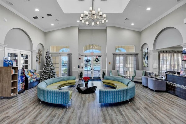 A spacious lobby with a central seating area, a Christmas tree, and a reception desk. - Upstay Great 3BR Condo w Scenic Views & Patio (Orlando)