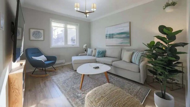 Una sala de estar con sofá, sillón mecedora, mesa de centro, televisor y candelabro.