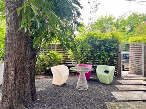 An outdoor seating area with a round table and two chairs, surrounded by a tree and various plants. - Ultimate 10br Group Getaway6min to Rainey Street (Austin)