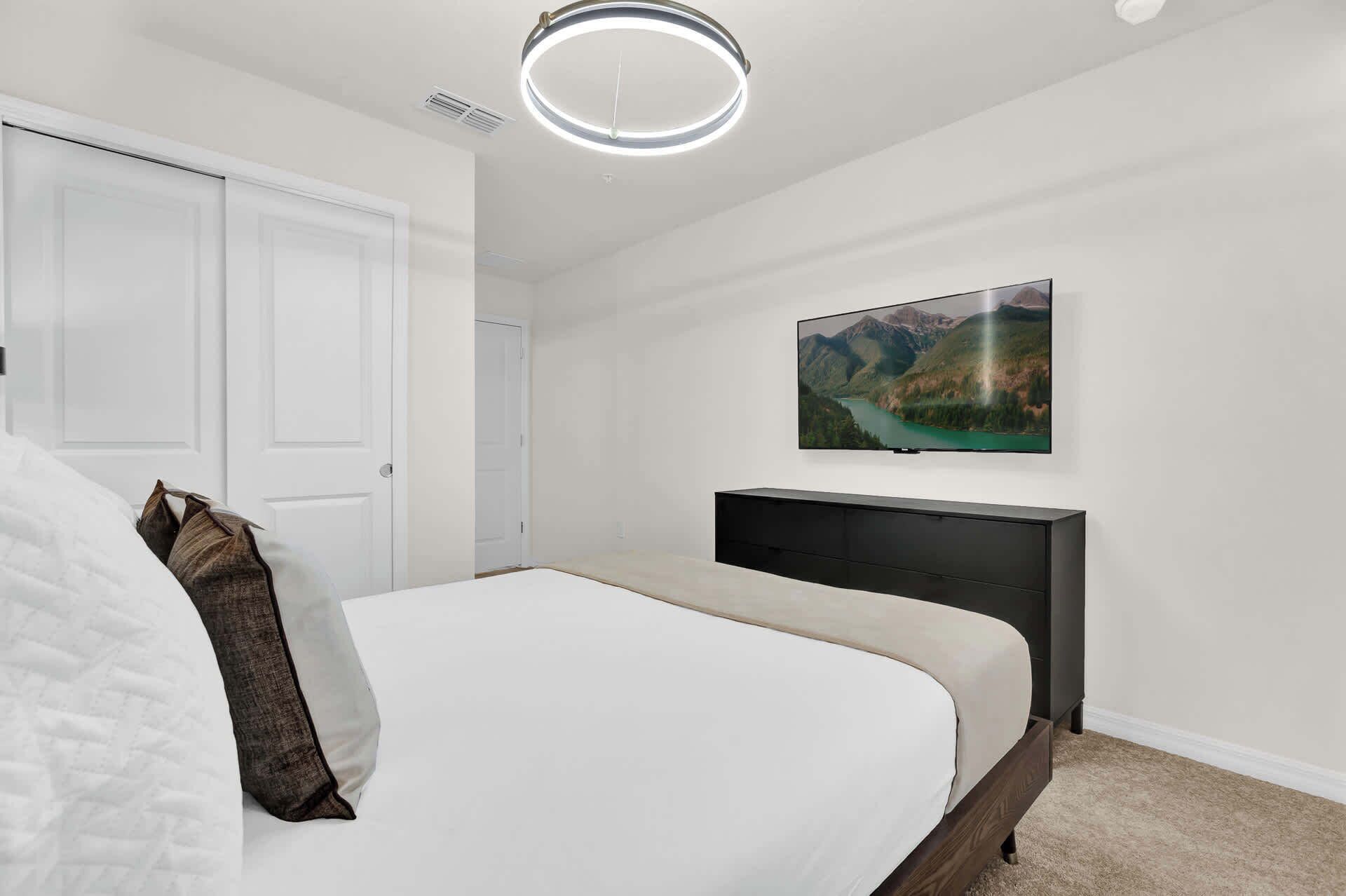 Una camera da letto con un letto, una TV a parete e una porta.