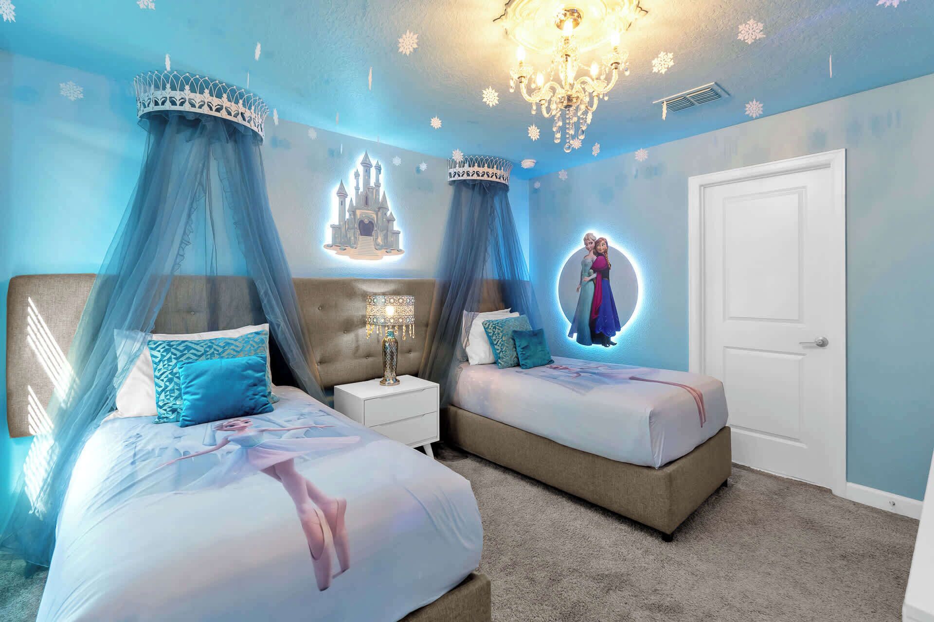 Une chambre avec deux lits, un lustre et des décorations murales représentant un château et des personnages.