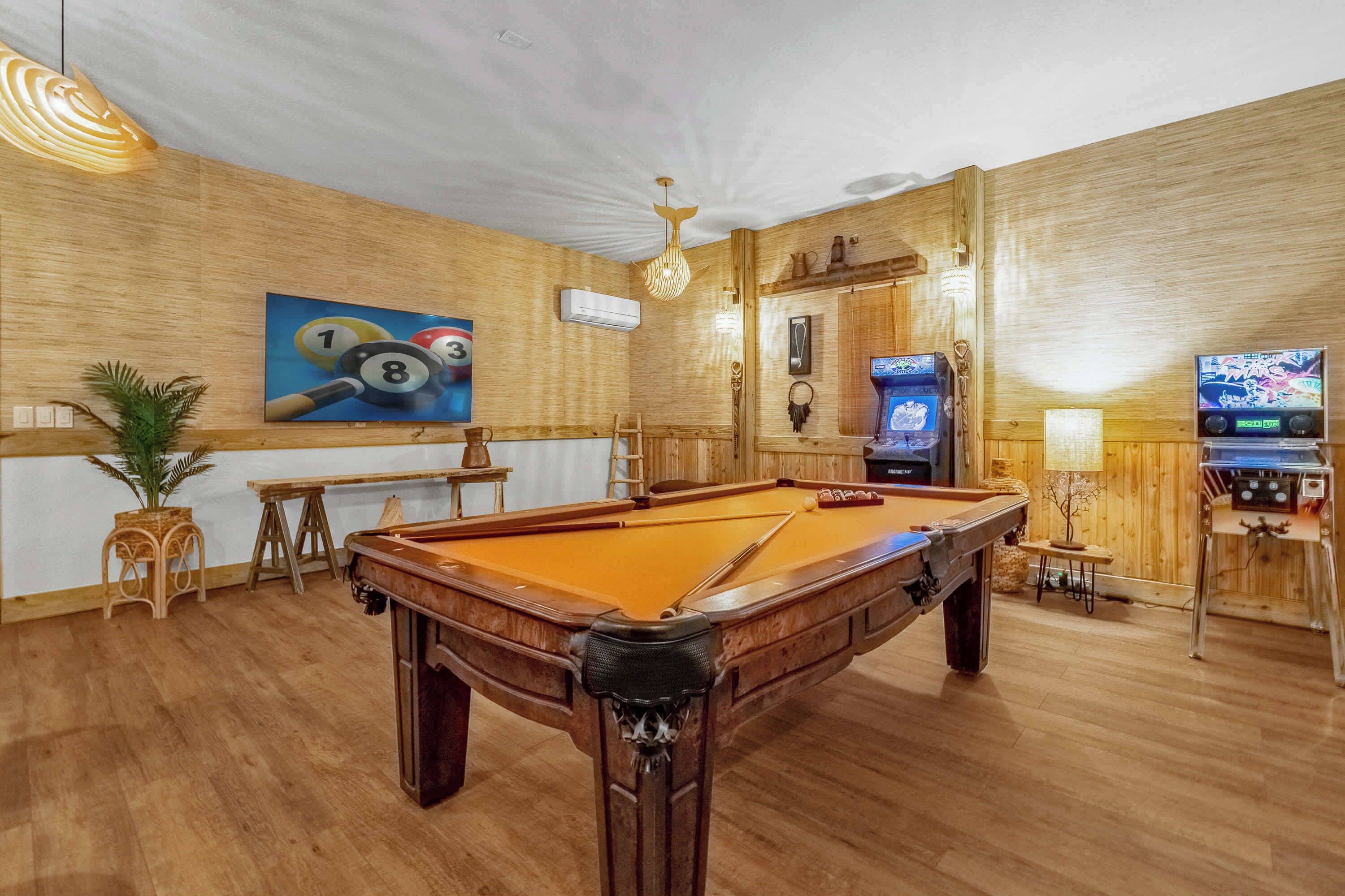 A pool table with a wooden finish, a ceiling fan, and a television screen displaying a game.