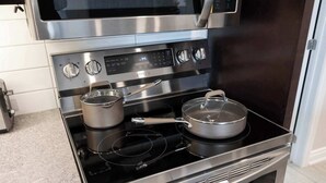 A stainless steel kitchen with a microwave above the stove, a pot on the burner, and a pan on the stovetop. - Stylish Modern Family Suite With Patio (Toronto)