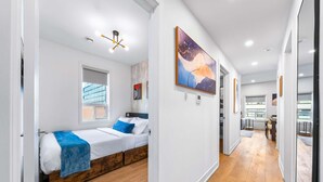 A modern bedroom with a bed, a window, and a hallway leading to a dining area. - The Mccaul Cozy DT Suite Near Fifa 2026 (Toronto)