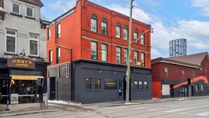 A red brick building with a black awning, a sign for 'The McCul' coffee shop, and a clear sky. - The Mccaul Cozy DT Suite Near Fifa 2026 (Toronto)