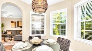 A dining area with a round table set for four, white plates, and a woven light fixture above. - Upstay: Pet-friendly Family Condo w Poolsleeps 8 (Winter Garden)