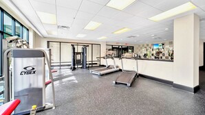 A gym with treadmills, a Cybex machine, and a weight bench. - Upstay - Condo Near Disney w Pool-spa-sauna-games (Winter Garden)