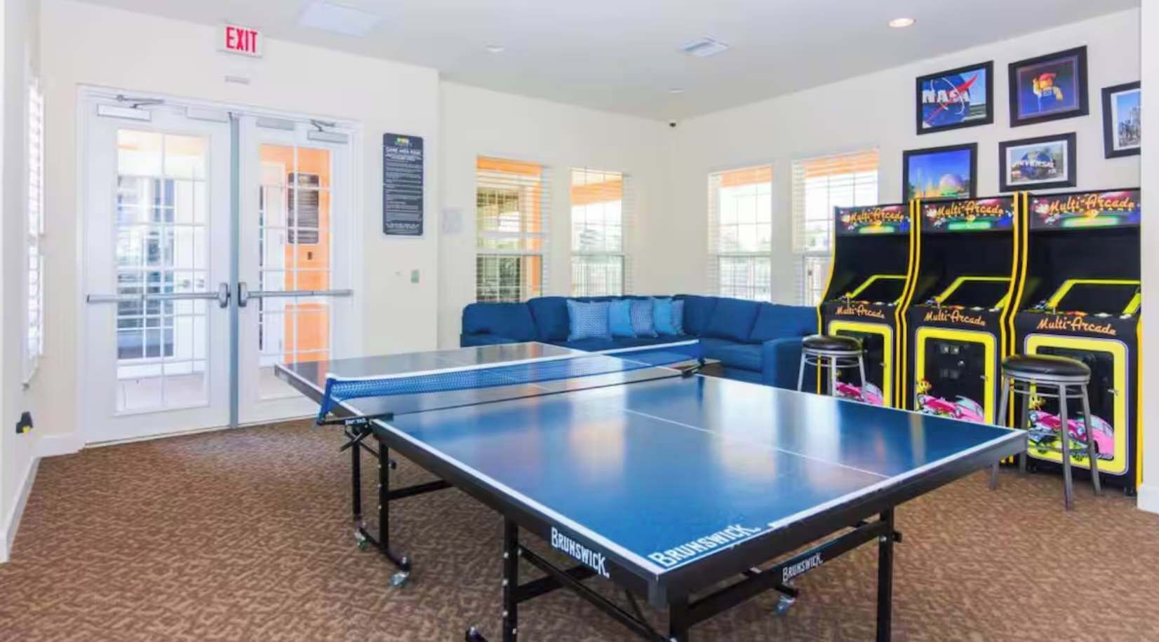A table tennis table, a sofa, arcade games, and an exit sign.