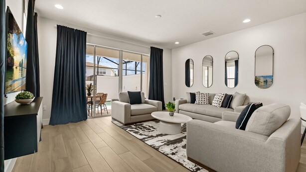 A modern living room with a sofa set, a coffee table, and a view of the outdoors through large windows. - Contemporary 4BR Townhome With Pool & Themed Rooms (Clermont)