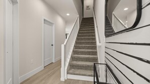 A staircase with carpeted steps and white railings, leading to an upper floor. - Contemporary 4BR Townhome With Pool & Themed Rooms (Clermont)