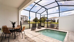 A covered outdoor area with a pool, chairs, and a table. - Contemporary 4BR Townhome With Pool & Themed Rooms (Clermont)