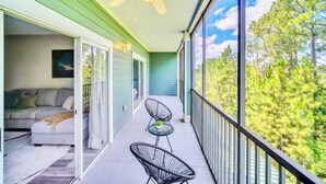 Un balcon doté d’un ventilateur de plafond, d’un canapé, de deux fauteuils et d’une table agrémentée d’une plante.