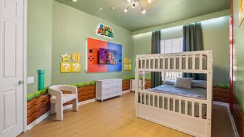 A child's room with a bunk bed, a desk, and a chair.