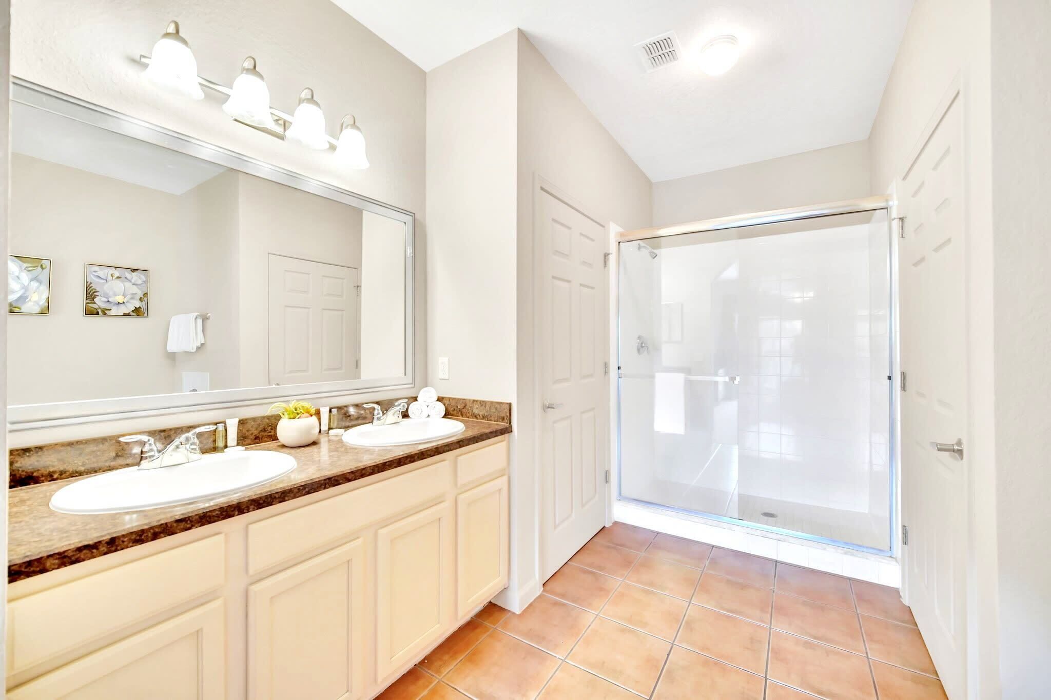 A bathroom with a double sink, a large mirror, and a glass shower enclosure.