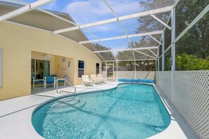 Une piscine dotée d’un espace couvert, de chaises longues et d’une clôture blanche.