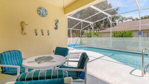 Un espace aménagé au bord de la piscine, comprenant un coin salon couvert, une piscine et une vue sur les environs.