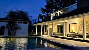 A modern two-story house with a swimming pool, outdoor seating, and a stone facade. - Upstay Modern Home Near Golf Course and Downtown (Austin)