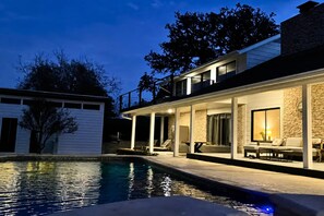 A modern two-story house with a swimming pool, outdoor seating, and a stone facade. - Upstay Modern Home Near Golf Course and Downtown (Austin)