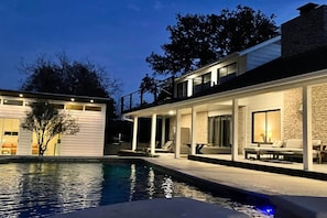 A modern two-story house with a swimming pool, outdoor seating, and a stone facade. - Upstay Modern Home Near Golf Course and Downtown (Austin)
