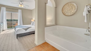 A bedroom with a large bed, a bathroom with a bathtub, and a balcony with a view. - Bright Family Escape With Game Room and Sauna (Winter Garden)