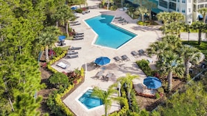 An aerial view of a resort with a large swimming pool, sun loungers, and palm trees. - Bright Family Escape With Game Room and Sauna (Winter Garden)