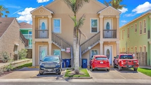A multi-story residential building with a central staircase, parking spaces, and a palm tree in the middle. - Beachfront South Padre Retreat w/ Balcony & Pool (South Padre Island)