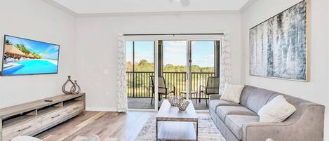 Ein Wohnzimmer mit Fernseher, einer Couch, einem Couchtisch und einem Balkon mit Blick.